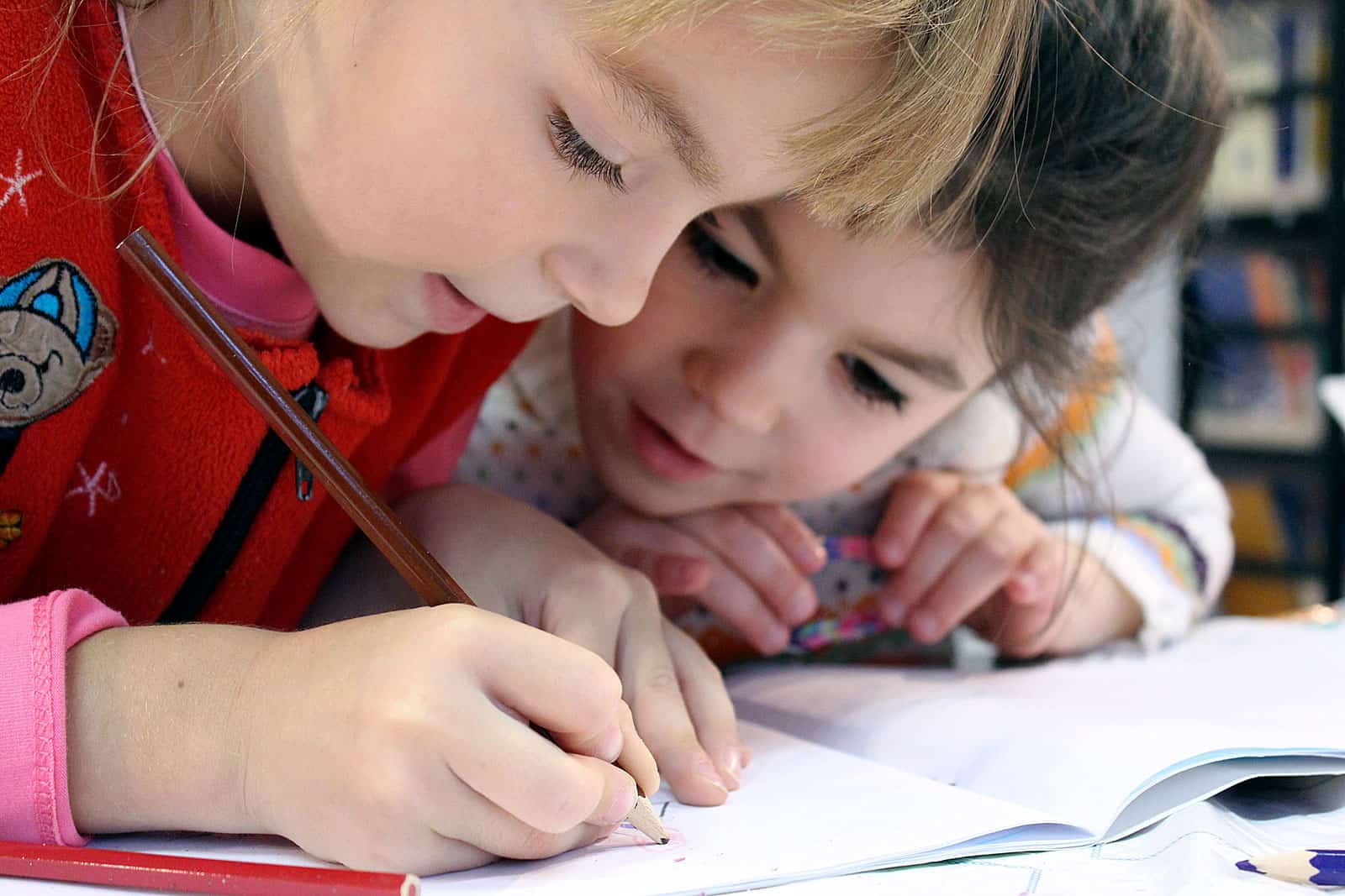 Crianças a desenhar num caderno.
